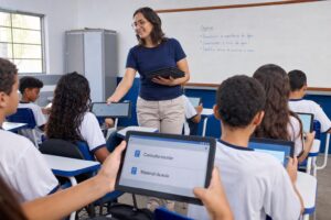 Professora distribuindo tablets Android aos alunos em sala de aula